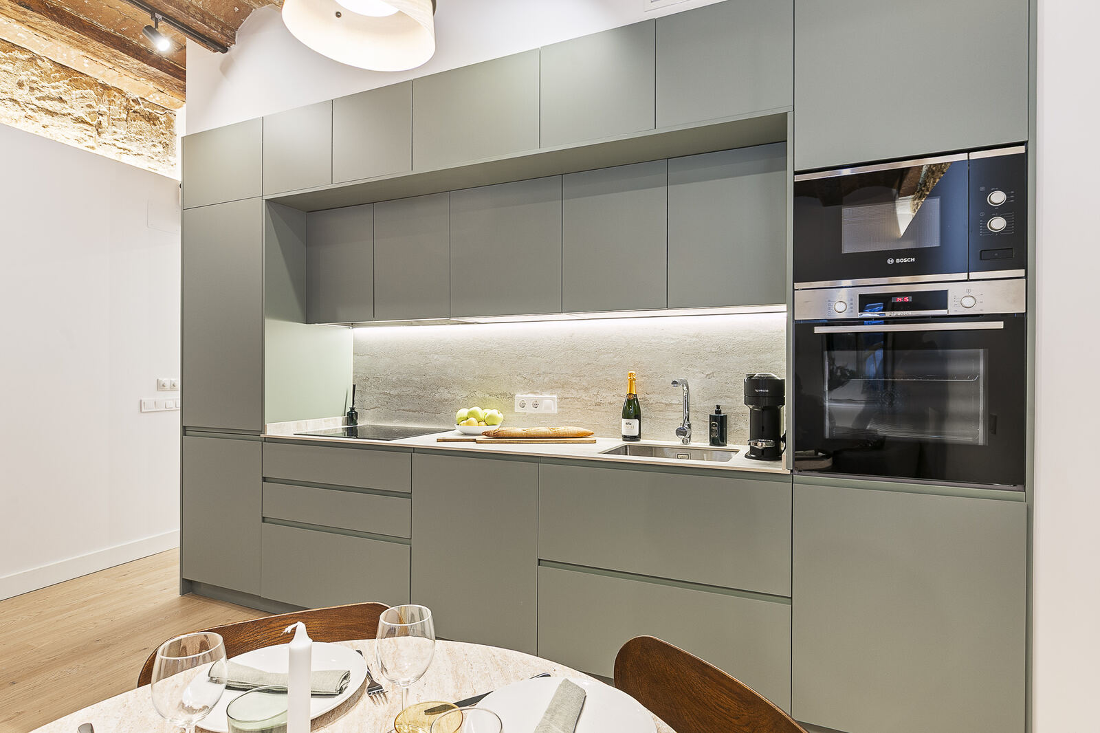 Kitchen after renovation — sage cabinetry, integrated Bosch appliances, exposed brick vault
