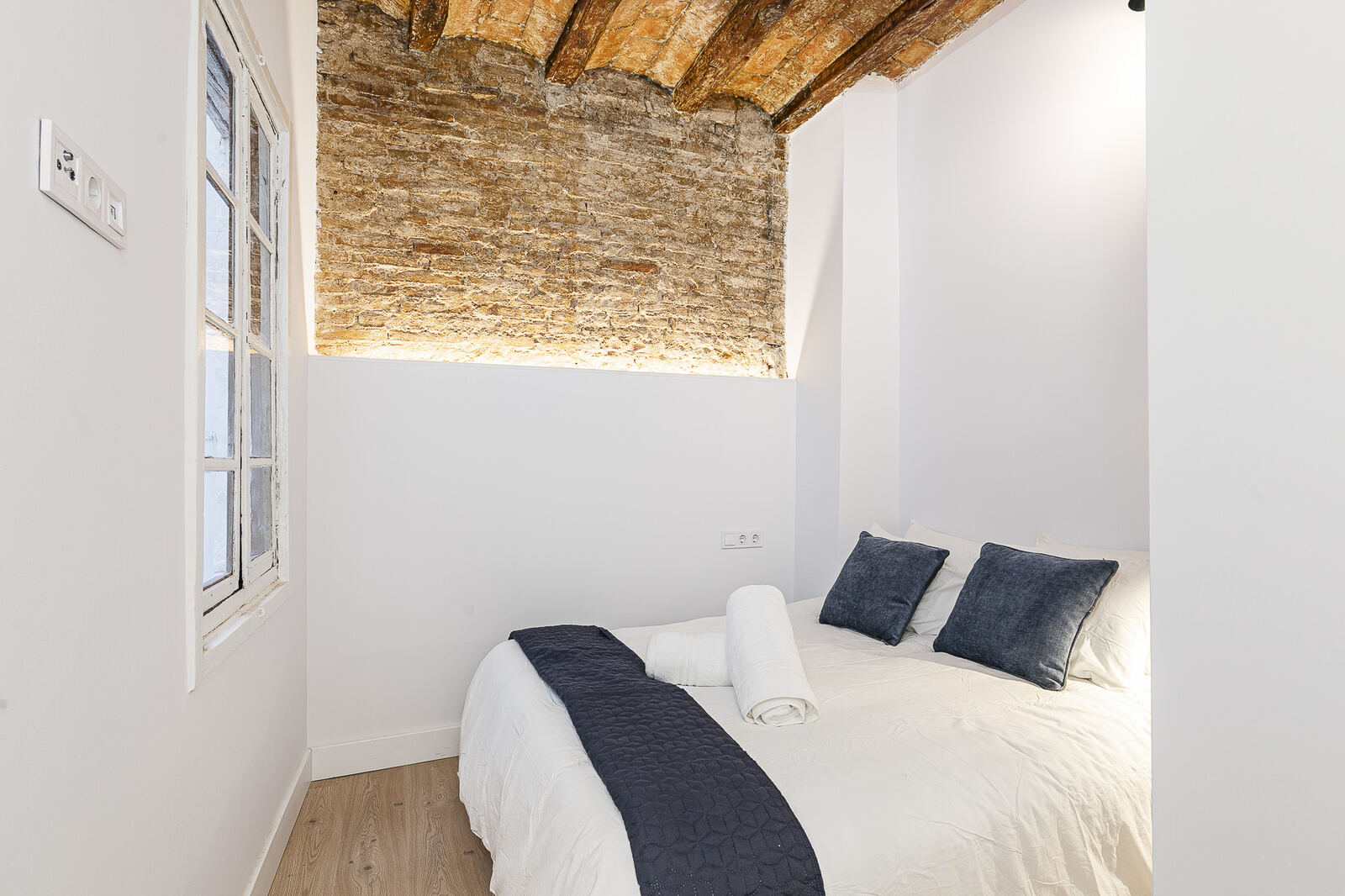Bedroom after renovation — exposed brick vault, neutral palette, new oak floor