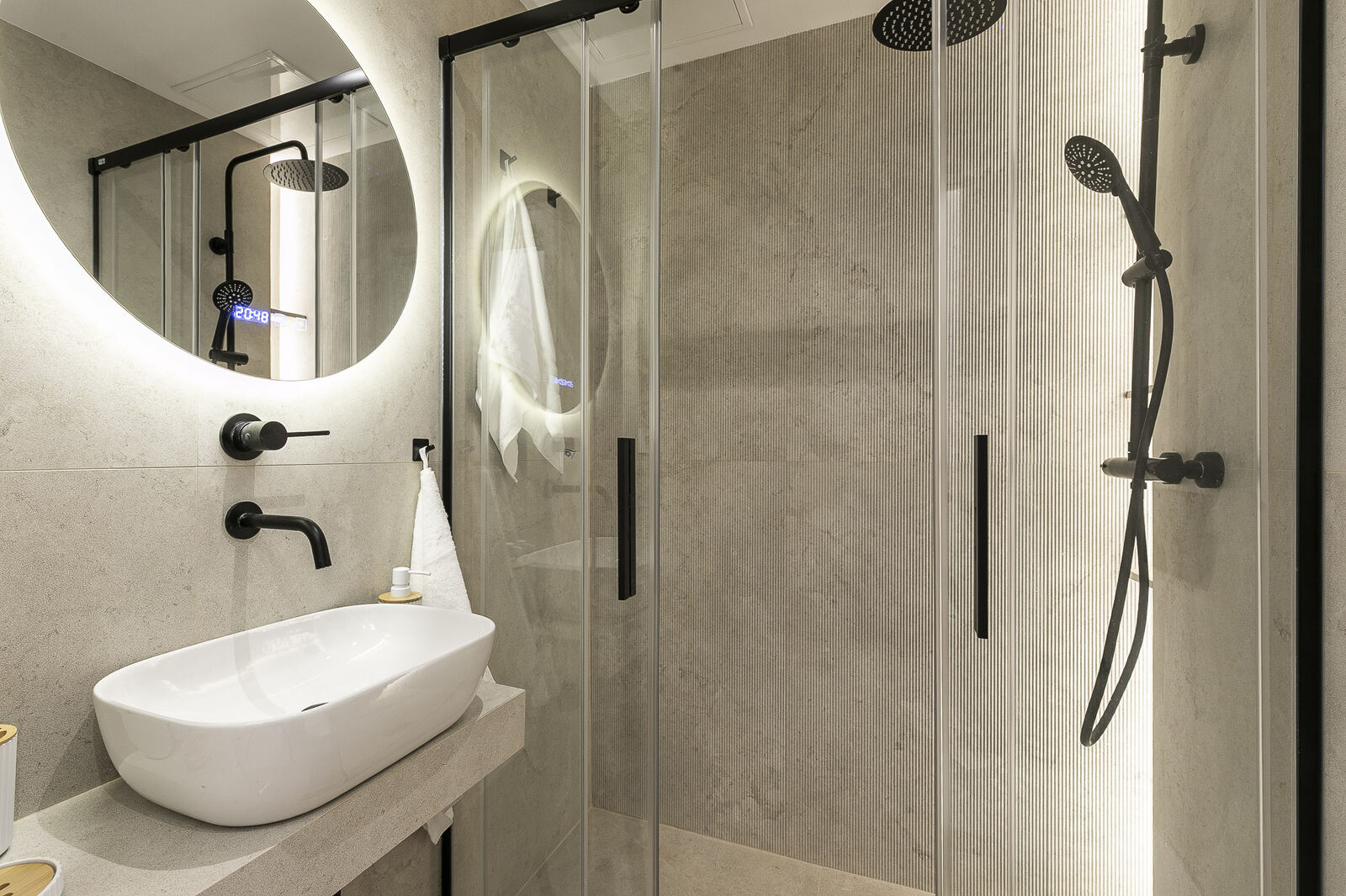 Bathroom after renovation — stone-tiled walls, walk-in shower, matte black fixtures