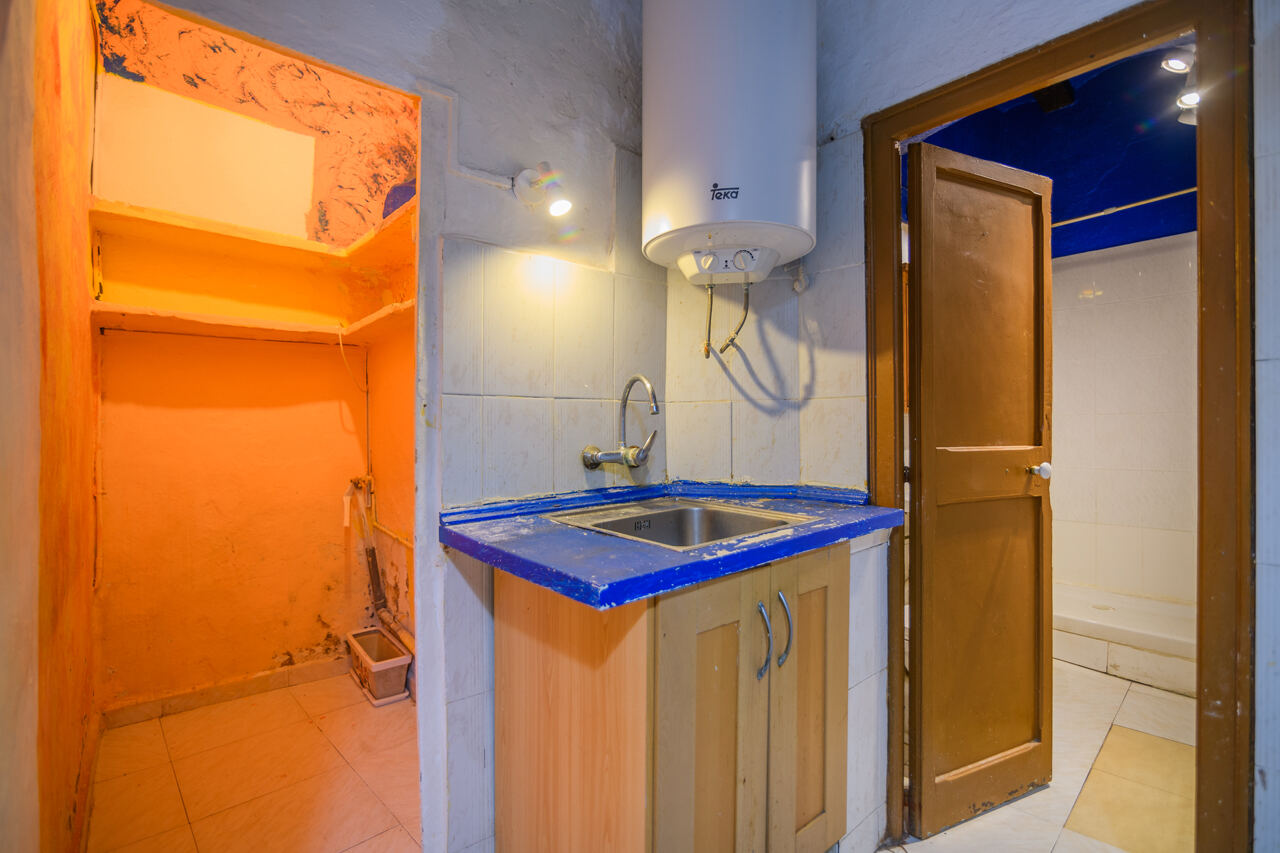 Kitchen before renovation — old cabinet, exposed water heater, blue countertop